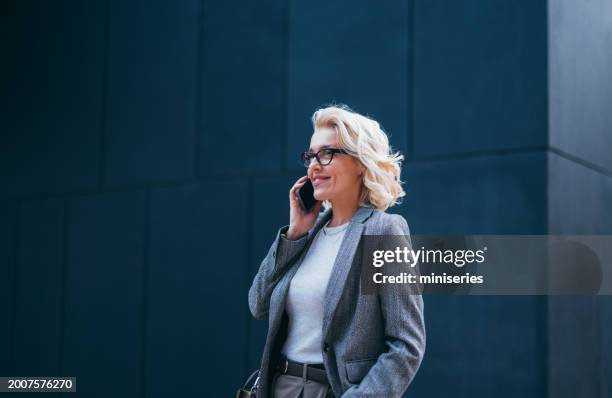 porträt einer schönen blonden geschäftsfrau, die außerhalb des büros telefoniert - einzelne frau über 40 stock-fotos und bilder