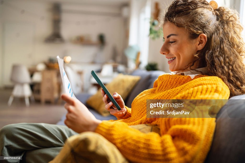 Young woman using e-banking to pay bills from home