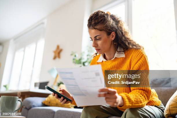 while organizing home finances, woman using mobile phone to calculate - räkning bildbanksfoton och bilder