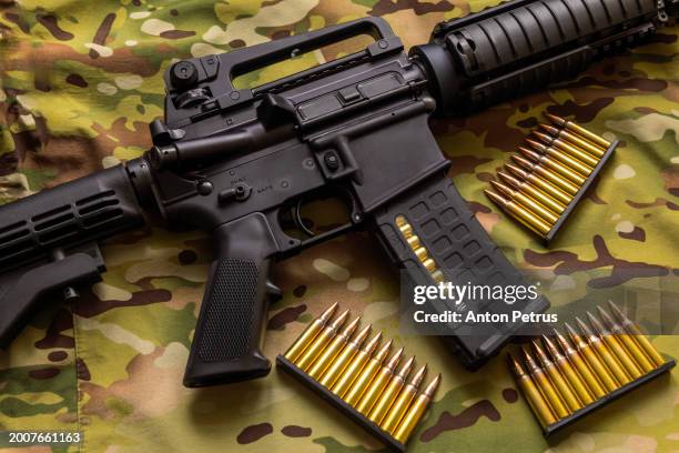 m4 carbine against a camouflage background - maschinengewehr stock-fotos und bilder