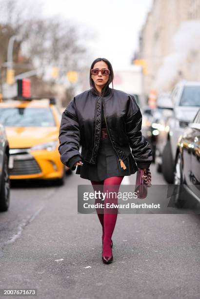 Samia Laaboudi wears Oleyeke black cropped padded nylon bomber, Aritzia black pleated mini skirt, Themoirè oversize burgundy dioni canvas bag with a...