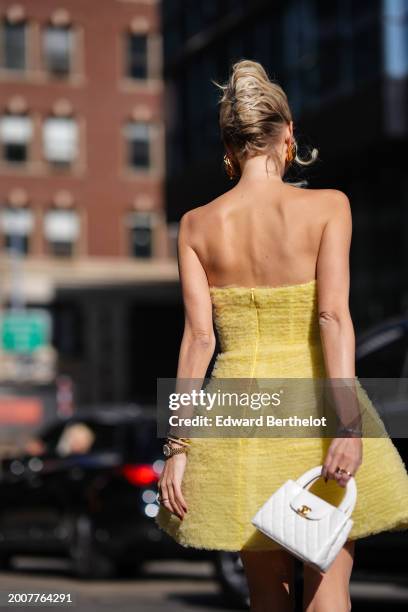 Leonie Hanne wears heart-shaped golden earrings , a yellow off-shoulder low-neck tweed mini puff skirt / back-nude, a white quilted leather Chanel...