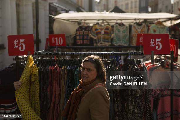 Price tags are seen on racks of clothes in a street market in Portobello road, in west London on February 16, 2024. Britain is in recession, official...