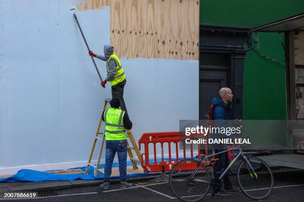 Workers paint boards outside a property on Portobello Road in west London, in west London on February 16, 2024. Britain is in recession, official...