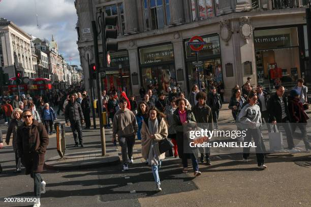 Pedestrians walk in the winter sunshine down Oxford Street in central London on February 16, 2024. Britain is in recession, official data showed...