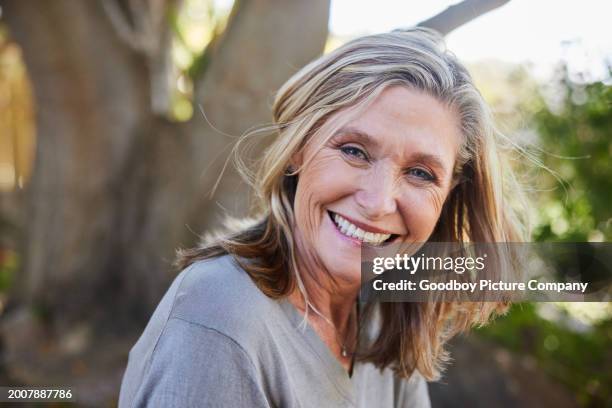 smiling mature woman sitting in her back yard at home - oudere vrouwen stockfoto's en -beelden