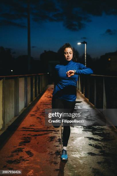 una donna sta facendo esercizi di stretching in città di notte - marcare sport foto e immagini stock