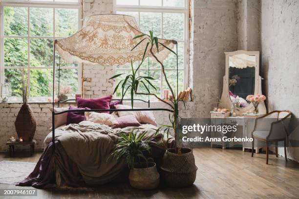 beautiful vintage bedroom with bed, cupboard, stylish decorations and large windows. loft, botanic, tropical, rainforest style. - decorating loft ストックフォトと画像