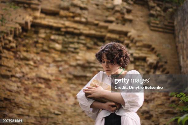 young woman holding brick while standing by ruined brick wall - shelling stock pictures, royalty-free photos & images