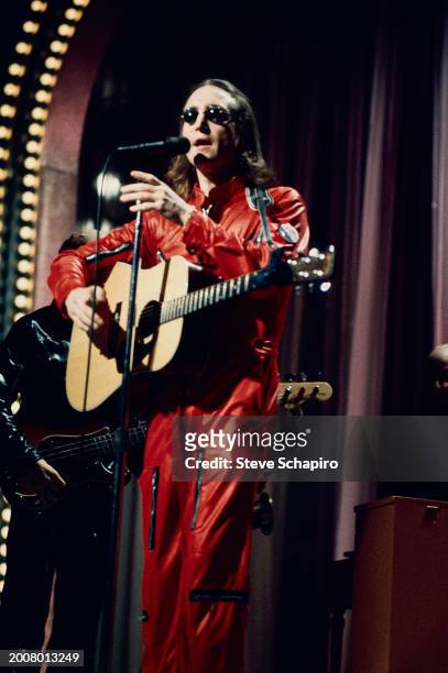 British Pop and Rock musician John Lennon plays acoustic guitar as he performs during the 'Salute To Sir Lew' tribute concert at the Hilton Hotel's...