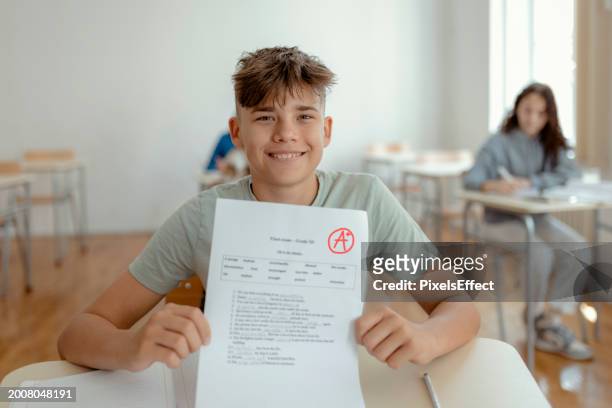 portrait of schoolboy with perfect grade - plus sign stock pictures, royalty-free photos & images