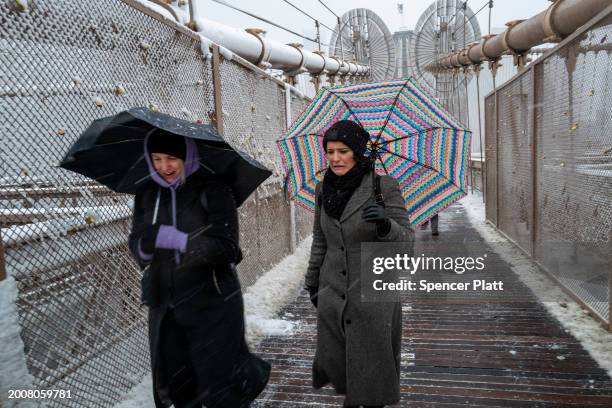 People walk across the Brooklyn Bridge in the blowing snow in Manhattan as a large winter storm makes its way across the area on February 13, 2024 in...