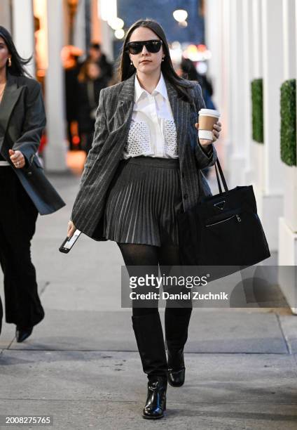 Guest is seen wearing a gray striped blazer, white button down shirt, gray skirt and black boots with black bag and black sunglasses outside the...