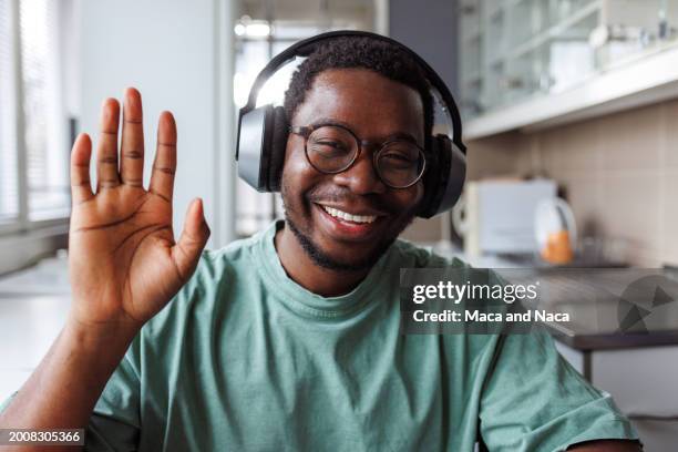 young man on a video call at home - waving stock pictures, royalty-free photos & images