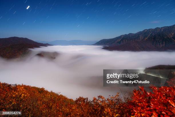 the beautiful sight of clouds cascading down and star trails at mount echigo komagatake in niigata - echigo yuzawa stock pictures, royalty-free photos & images