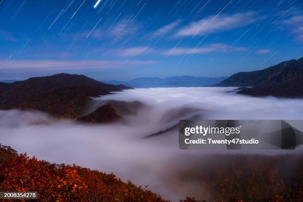 the beautiful sight of clouds cascading down and star trails at mount echigo komagatake in niigata - echigo yuzawa stock pictures, royalty-free photos & images