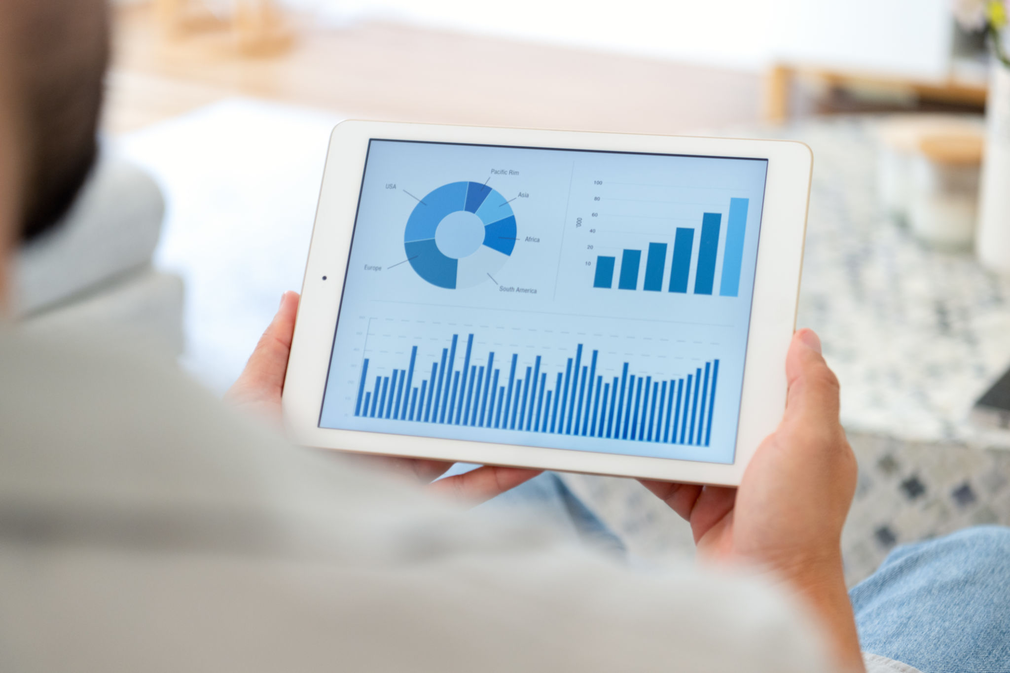 Man working on a digital tablet with financial data at home. Close up of device showing charts and graphs. Man working on a digital tablet with financial data at home. Close up of device showing charts and graphs.