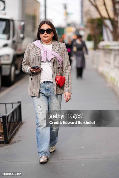 Guest wears sunglasses, a rhinestones / bejeweled necklace, a white t-shirt, a beige checkered / checked pattern printed blazer jacket , ripped blue...