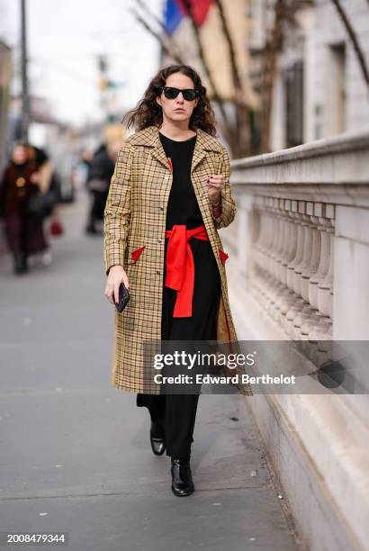 Guest wears sunglasses, a yellow checkered / checked pattern printed trench long coat , a black top, an orange belt made of a pullover around the...