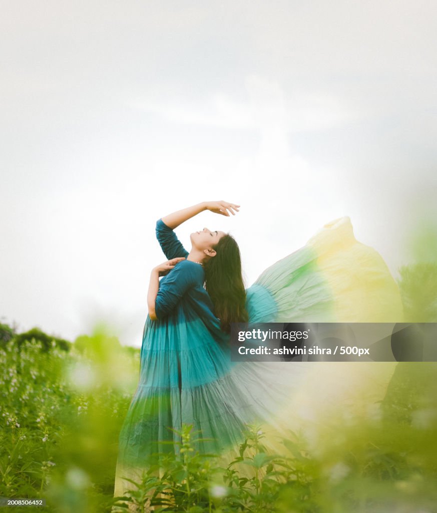 Young woman in dress standing on field against sky,India