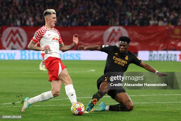 Benjamin Sesko of RB Leipzig is tackled by Aurelien Tchouameni of Real Madrid during the UEFA Champions League 2023/24 round of 16 first leg match...