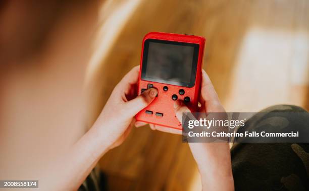 top down image of a child's hands playing a red handheld games console - handheld game console fotografías e imágenes de stock