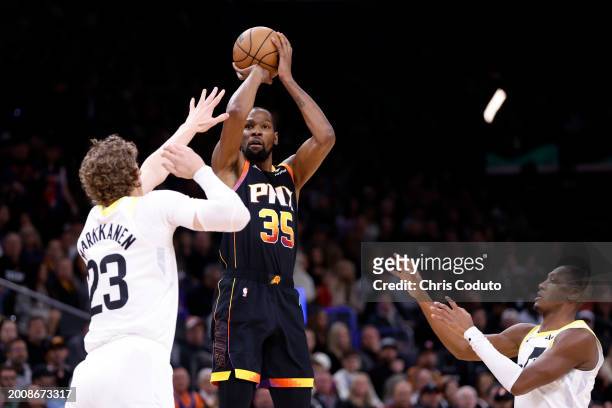 Kevin Durant of the Phoenix Suns attempts a three-point shot over Lauri Markkanen of the Utah Jazz and Kris Dunn during the game at Footprint Center...