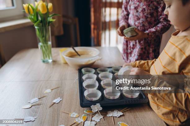 children preparing easter muffins at home - cake case stock pictures, royalty-free photos & images