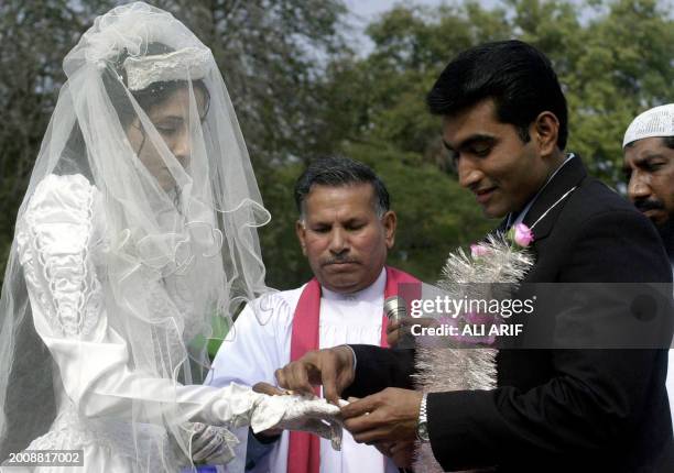 Christian groom presents a wedding ring to his bride during a mass marriage ceremony organized by various non governmental organisations ,...