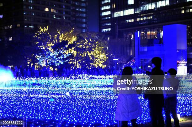 People admire the Christmas illuminations at Tokyo Midtown shopping mall in Tokyo on December 7, 2011. Christmas or Christmas Day is an annual...