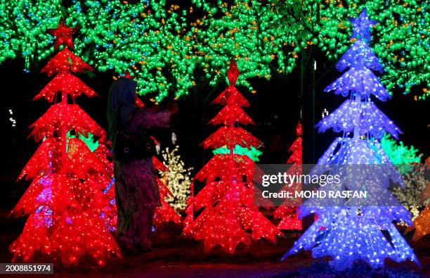 Visitor takes pictures of Christmas trees illuminated by LED lights in Shah Alam, some 25 kilometres west of the country's capital Kuala Lumpur on...