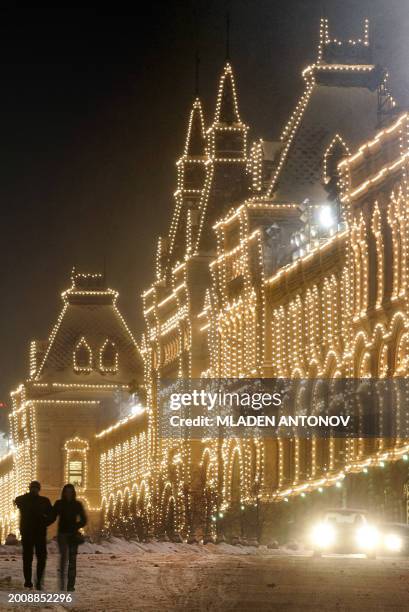 Couple walks next to the illuminated building of the main Moscow's department store GUM on the Red Square, 21 December 2005. Moscow prepares for the...