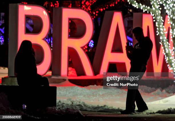 People are taking photos, silhouetted against part of a sign near Gage Park in downtown Brampton, Ontario, Canada, on February 16, 2024.