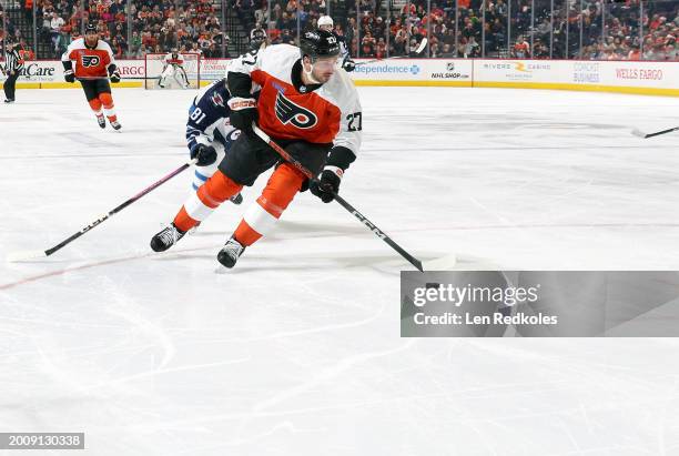 Noah Cates of the Philadelphia Flyers skates the puck against Kyle Connor of the Winnipeg Jets at the Wells Fargo Center on February 8, 2024 in...