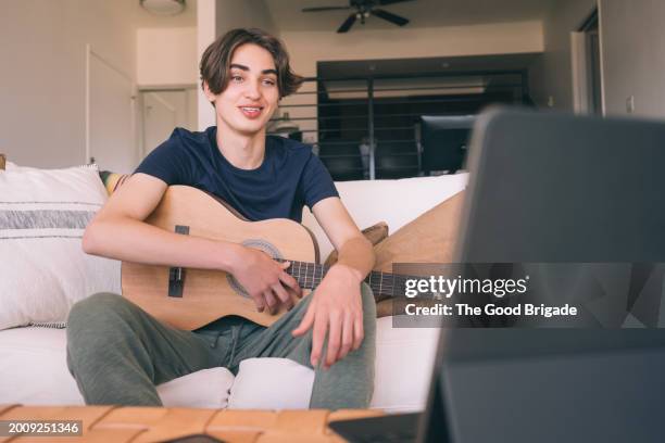 teenage boy learning to play guitar online at home - malibu home stock pictures, royalty-free photos & images