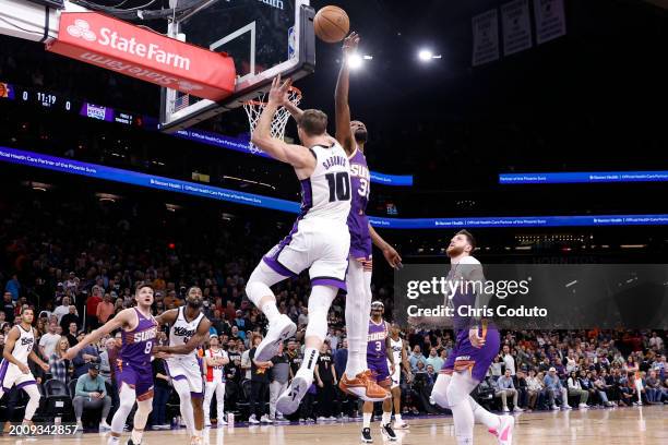 Kevin Durant of the Phoenix Suns blocks a shot by Domantas Sabonis of the Sacramento Kings during the first half at Footprint Center on February 13,...