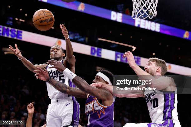 Royce O'Neale of the Phoenix Suns attempts to control a rebound against Domantas Sabonis and De'Aaron Fox of the Sacramento Kings during the first...