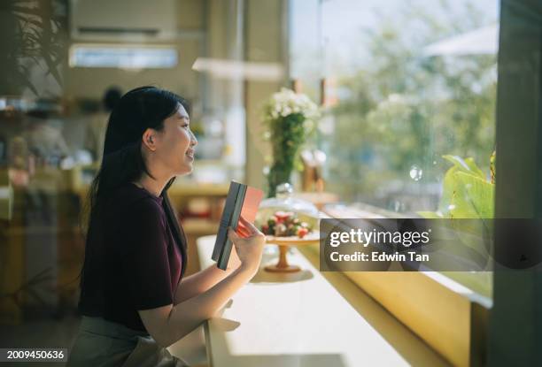 asian chinese woman reading book in cafe day dreaming - me time stock pictures, royalty-free photos & images