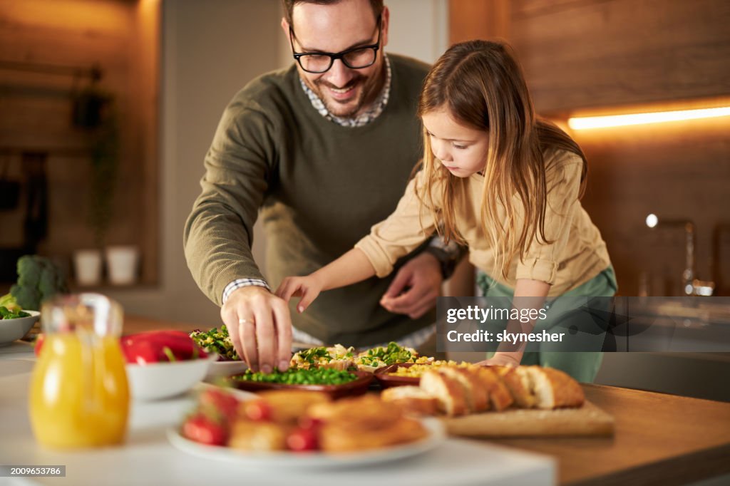 Happy father and his small girl enjoying while making sandwiches in the kitchen.