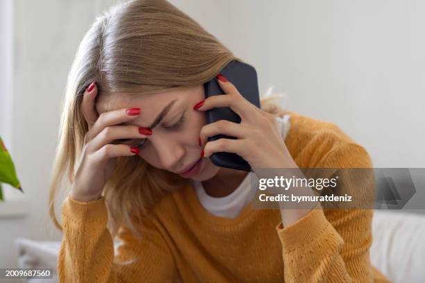 woman looking stressed while talking on her phone - ear stock pictures, royalty-free photos & images
