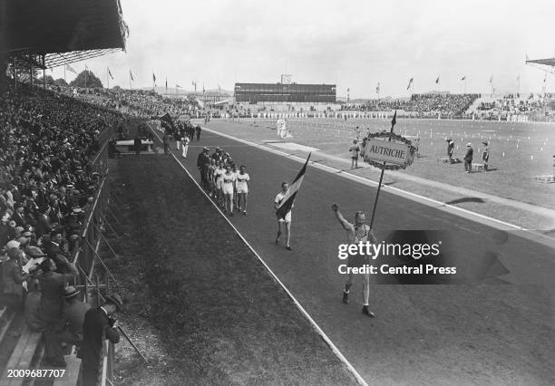 An Austrian athlete carrying the 'Autriche' placard leads the flagbearer and the Austrian team, gives the Olympic salute during the opening ceremony...