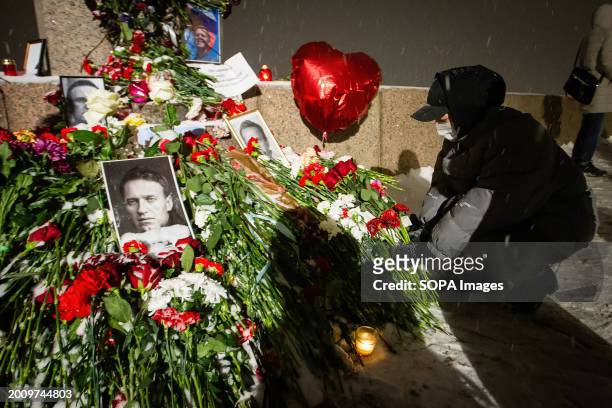 Mourner lays flowers at a spontaneous memorial in memory of the deceased Russian opposition leader Alexei Navalny, organized at the monument to...