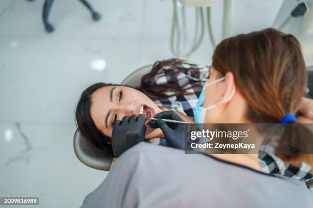part of a series: a female dentist is performing the implant treatment on a woman patient lying in the dental chair. - implante imagens e fotografias de stock