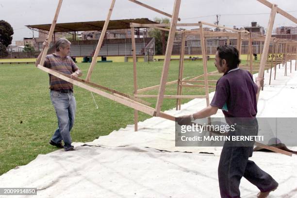 Two electoral workers install the booths that will serve as voting centers in the municipal stadium of Soacha, el 25 May 2002. AFP PHOTO Martin...