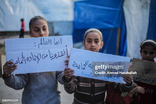 Palestinian children hold placards during a march demanding an end to the war and their right to live, education and play on February 14, 2024 in...