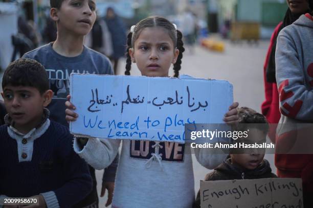 Palestinian children hold placards during a march demanding an end to the war and their right to live, education and play on February 14, 2024 in...