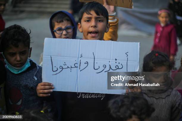 Palestinian children hold placards during a march demanding an end to the war and their right to live, education and play on February 14, 2024 in...