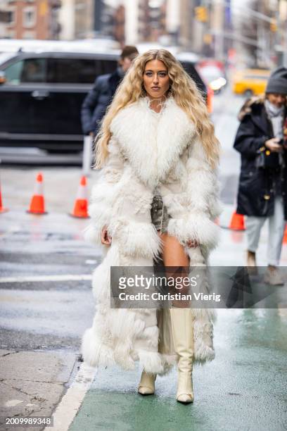 Emili Sindlev wears white fur coat, creme white boots, shorts outside Michael Kors on February 13, 2024 in New York City.
