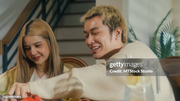 group of young asian people preparing and having fun sitting at dining table at home. multicultural friends having fun together college house party. - service of thanksgiving stock pictures, royalty-free photos & images