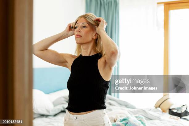woman with cancer wearing wig while standing in bedroom at home - wig stock pictures, royalty-free photos & images